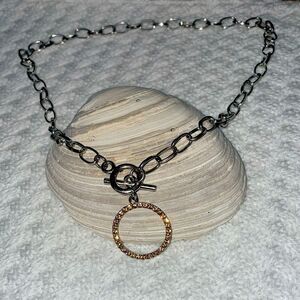 This is a silver necklace with a gold diamond ring design with a lariat clasp